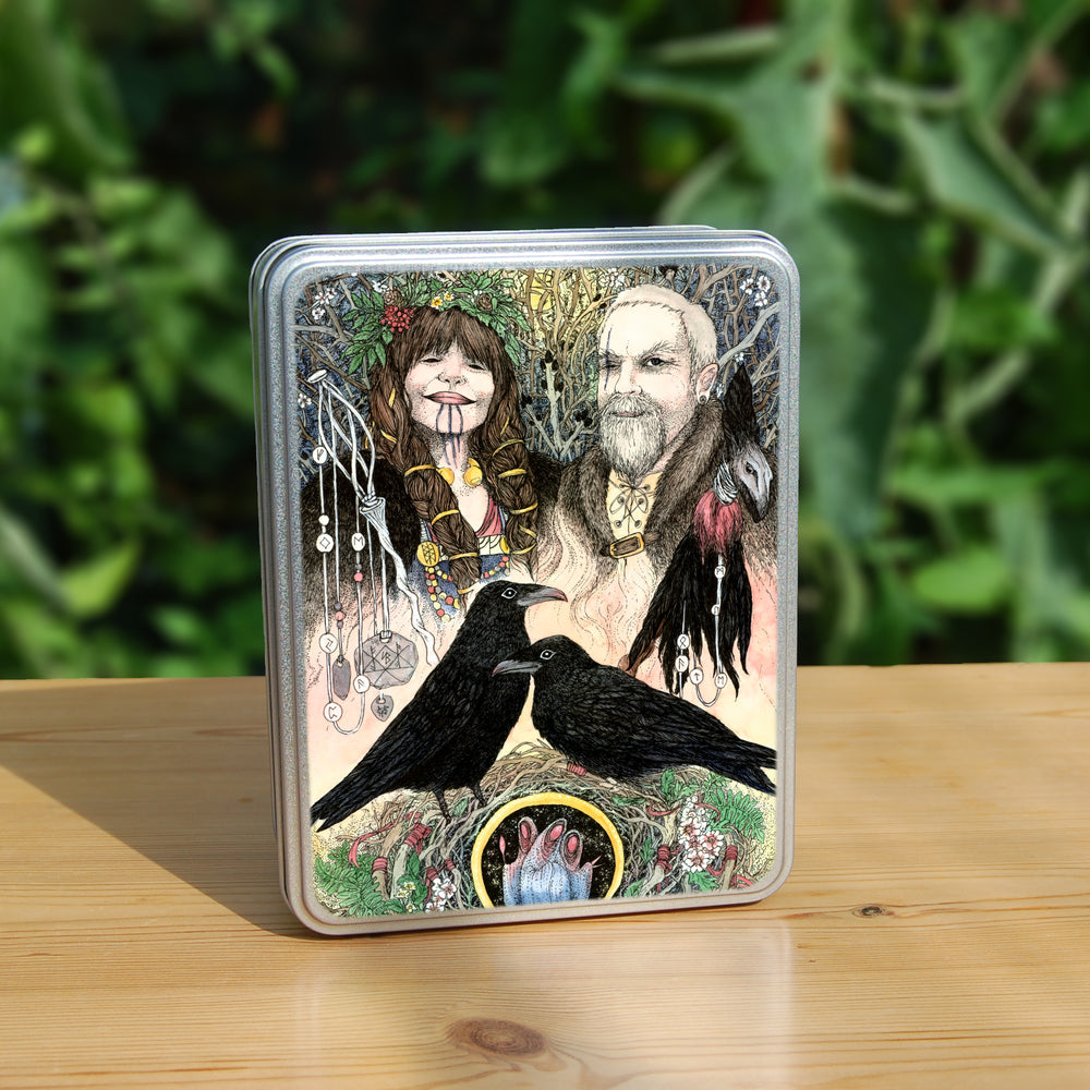 The head and shoulders of a woman (on the left) and a man (right) stand together, facing the viewer. The woman has long, plaited and bound brown hair, three drawn lines from her lip to her neck, and wears a garland on her head. To her side sits a delicate staff with runes hanging from it. The man has just one eye, with a long scar going vertically through where it should be, and is wearing a fur coat. A shaman's rattle, with the appearance of being made from a raven's head and feathers, and with runes hangi