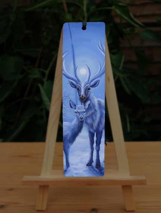 A stag and doe stand facing each other, heads turned towards the viewer. The design is cast in shades of blue. Snow lies underfoot. A wintery moon rises from between the stag's antlers, and stars can be seen in the sky beyond.