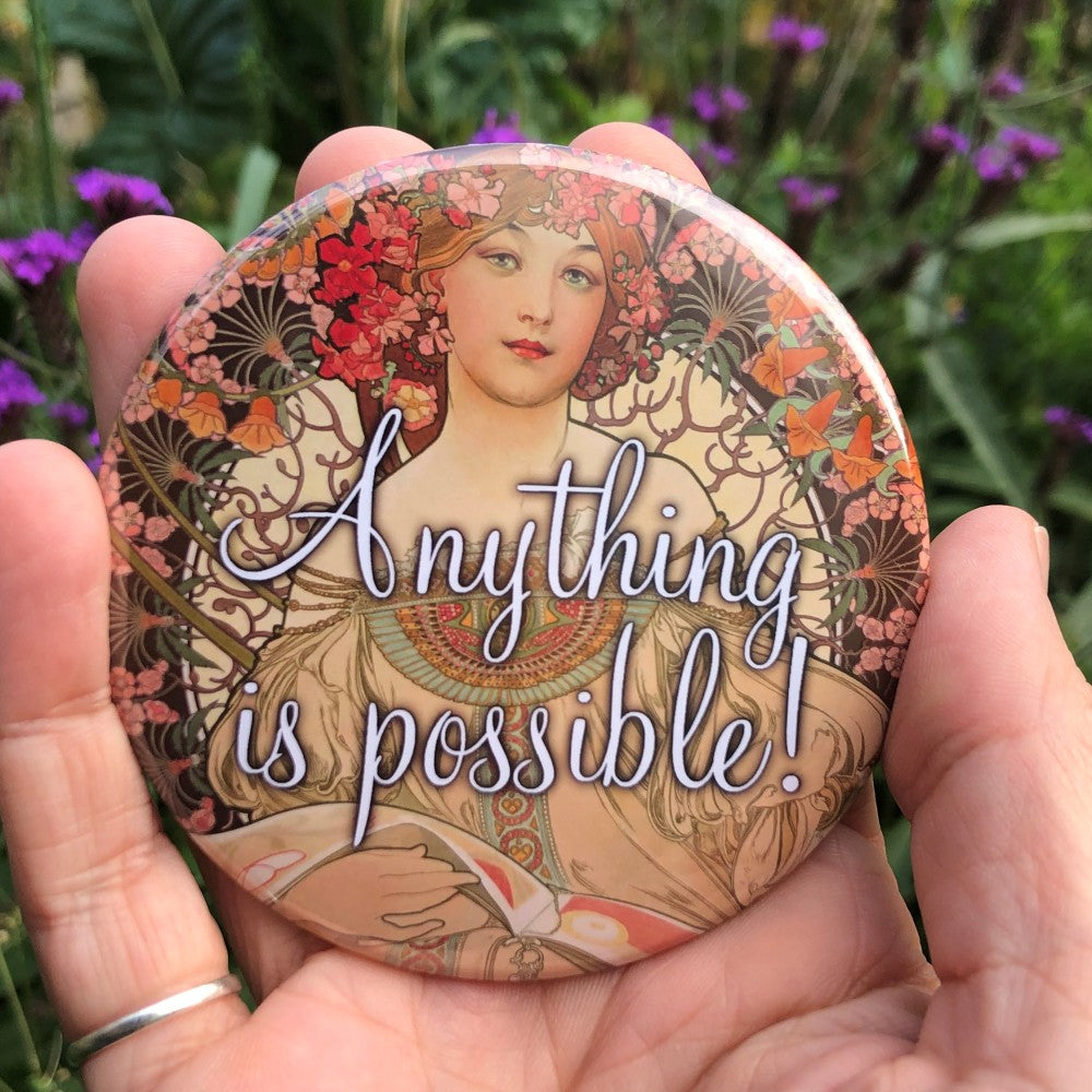 Art Nouveau style image of a young woman with flowers in her hair, and a flower border around the top two-thirds of of the design. Colours are reds, oranges and cream. "Anything is possible!" is written in decorative white text over the centre of the design.