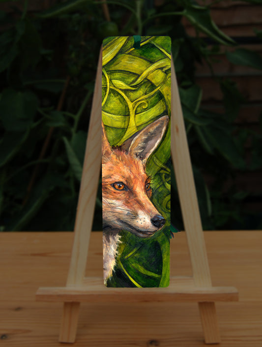 A tall bookmark: The head and neck of a red fox, their face angled towards the front right. The background consists of swirls of branches and leaves in a rich green colour.