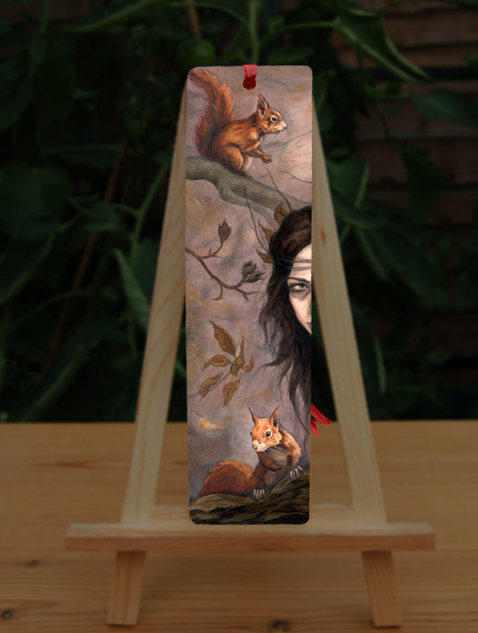 A tall bookmark: One side of the face of a young woman peers in from the right. A red squirrel sits on a branch above her, with another below her. Autumnal leaves and branches fill the scene. Colours are reds, oranges and browns.