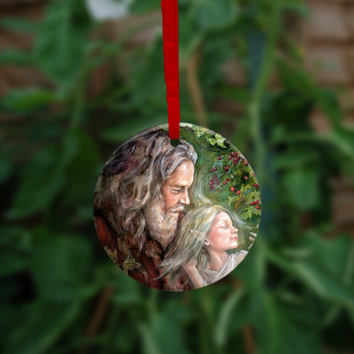 Circular hanging ornament with a red ribbon: An older man with long hair, grey beard, and wearing a red coat cradles a sleeping fairy, wearing a pale gossamer dress, in his arms. Branches of hawthorn and ivy fill the background.