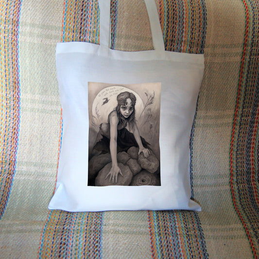 White tote bag: A young woman crouches on a pile of stones, her hands resting on stones in front of her. In front of the stones, a little lower down, is a stone with a round hole in it surrounded by a circular pattern. The woman wears a headband with a raven skull attached to the front. A full moon rises behind her, and a silhouette of a hare leaps in front of it. An inscription over the moon reads: Up from the earth with tooth and claw we rise. Stems and flowers fill the rest of the scene.