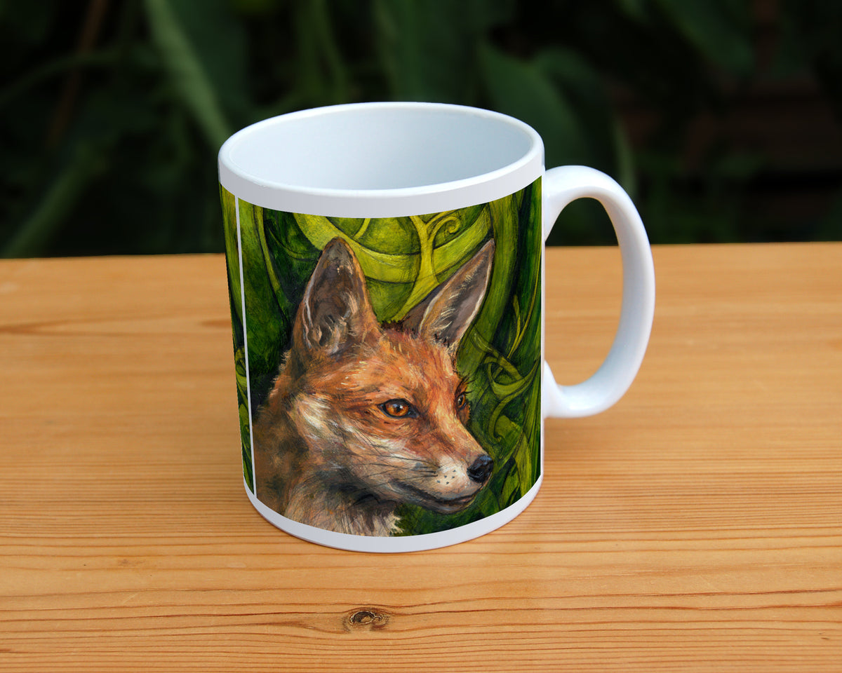 A white ceramic mug: The head and neck of a red fox, their face angled towards the front right. The background consists of swirls of branches and leaves in a rich green colour.