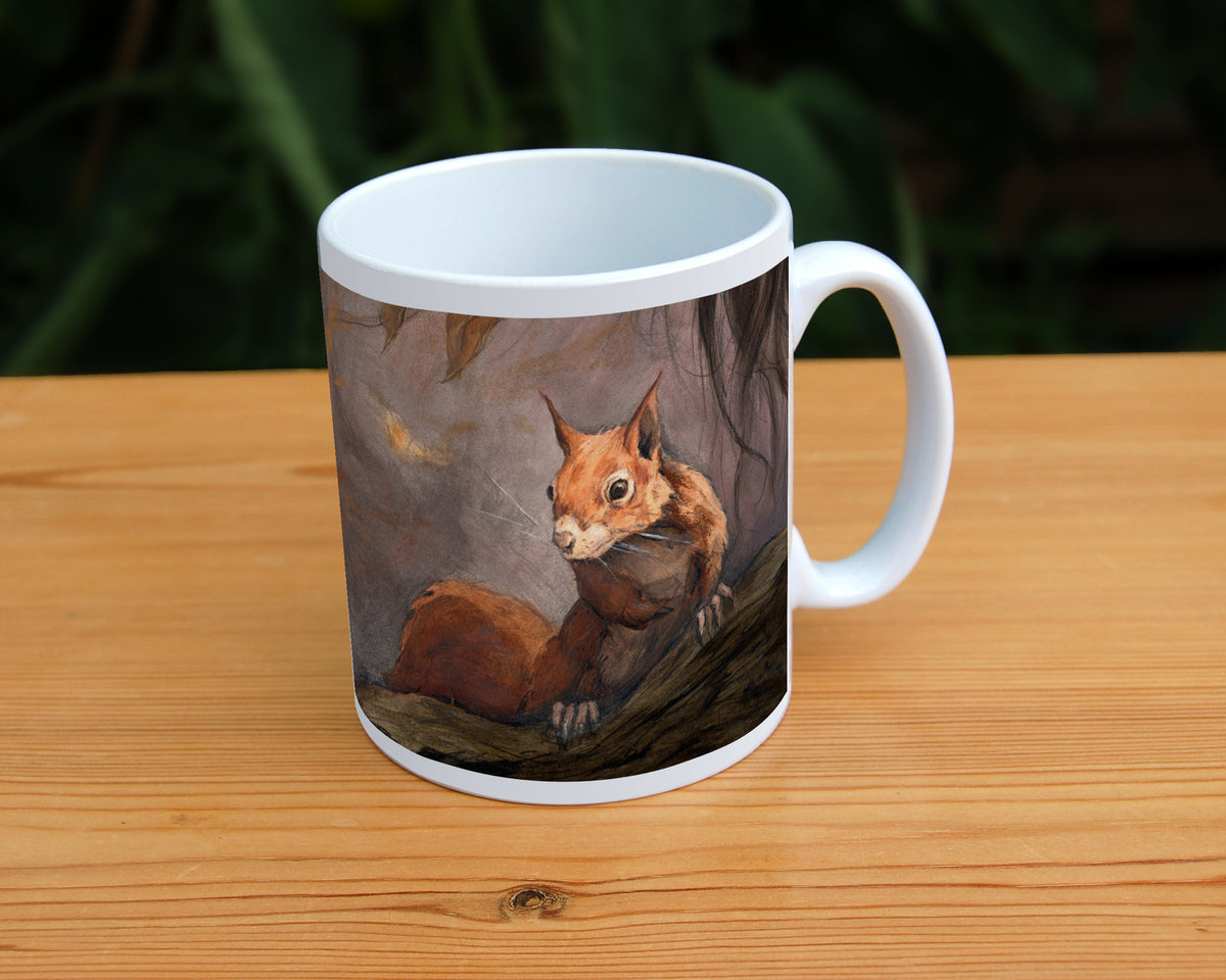 A white ceramic mug: A red squirrel sitting on a branch facing the viewer. Autumnal leaves and branches fill the scene. Colours are reds, oranges and browns.