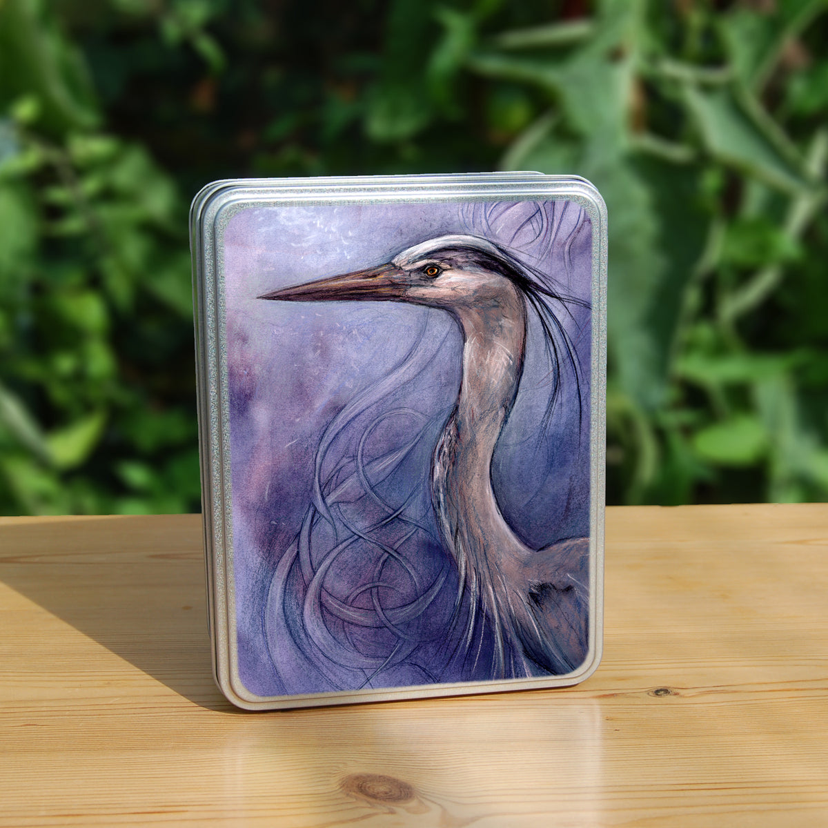 A rectangular tin: A sideways view of the head and neck of a heron. The background is a mottled purple with a swirl pattern.