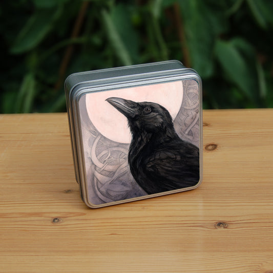 Square tin: The head and body of a raven standing facing towards the left, head tilted upward, behind which is a full moon. The background consists of swirls in a pale pink-brown colour.