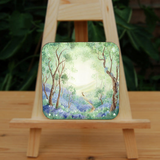 Trees reach upwards either side of a narrow winding path in woodland, the ground beneath them covered in bluebells. The path ends in the mid-distance, where a hare is sat. Beyond the hare, the trees open out to show hills in the distance. Colours are greens, blues and browns.