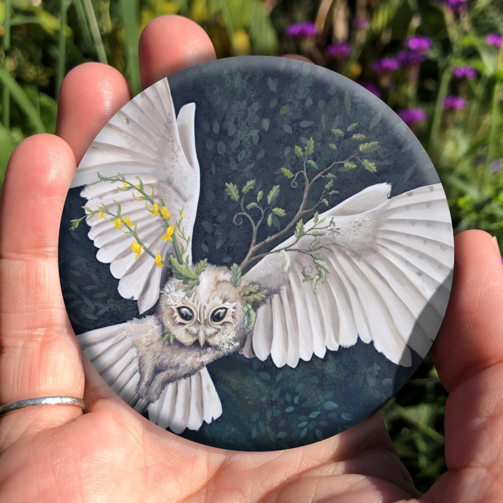 A white owl fills this painting as it flies from the bottom left towards top right. Stems of Meadowsweet with its yellow flowers sprout from the left side of her head, a young oak branch from the right.