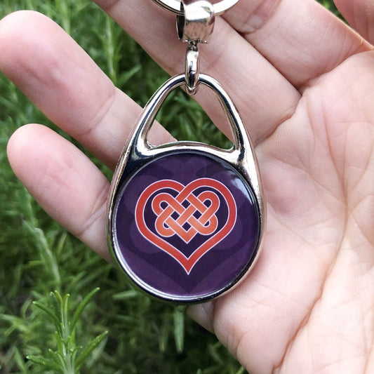 A heart shape which forms into a Celtic knot from the top and into the centre of the heart. The design is red with a white edge. The background is purple.